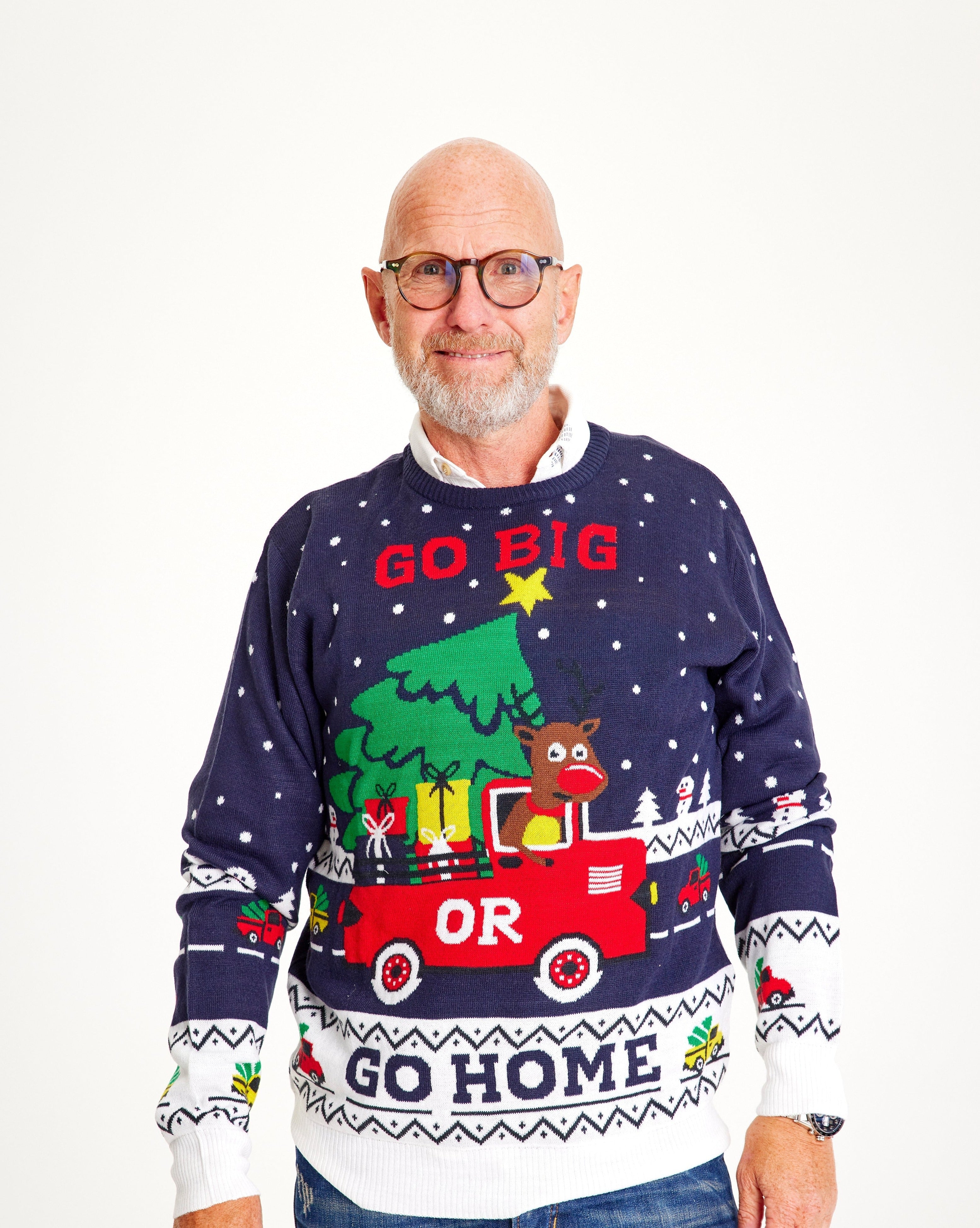 Un homme posant avec un pull de Noël portant la citation